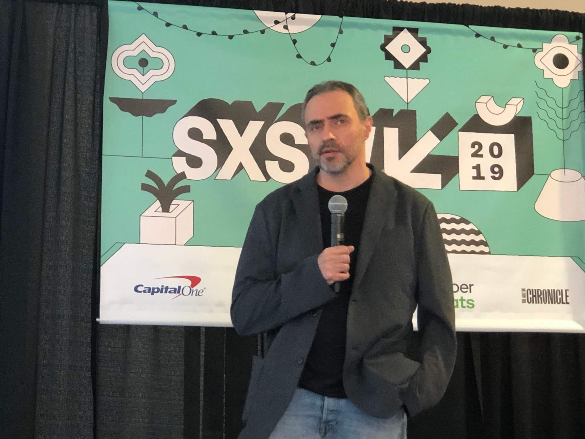 Juan Tubert speaking into a microphone in front of the SXSW 2019 backdrop